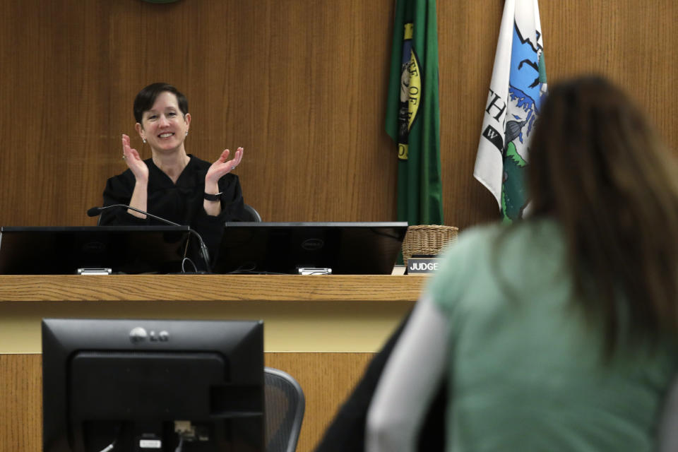 Thurston County Superior Court Judge Christine Schaller, left, applauds as Jamie Cline steps forward during a drug court session in Thurston County Superior Court Tuesday, Dec. 17, 2019, in Olympia, Wash. While in a jail work-release program this past spring, Cline, a heroin addict, took a medication called buprenorphine. A new treatment philosophy called "medication first" scraps requirements for counseling, abstinence or even a commitment to recovery. (AP Photo/Elaine Thompson)