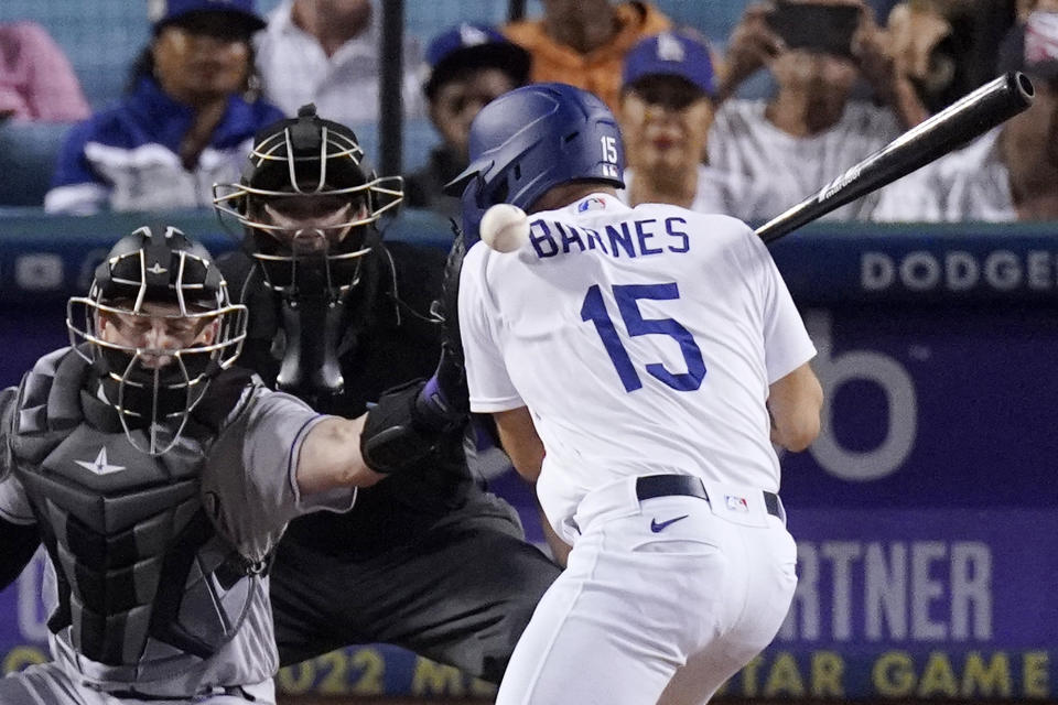 Los Angeles Dodgers' Austin Barnes, right, is hit in the back by a pitch as Colorado Rockies catcher Brian Serven, left, reaches for it during the seventh inning of a baseball game Wednesday, July 6, 2022, in Los Angeles. (AP Photo/Mark J. Terrill)