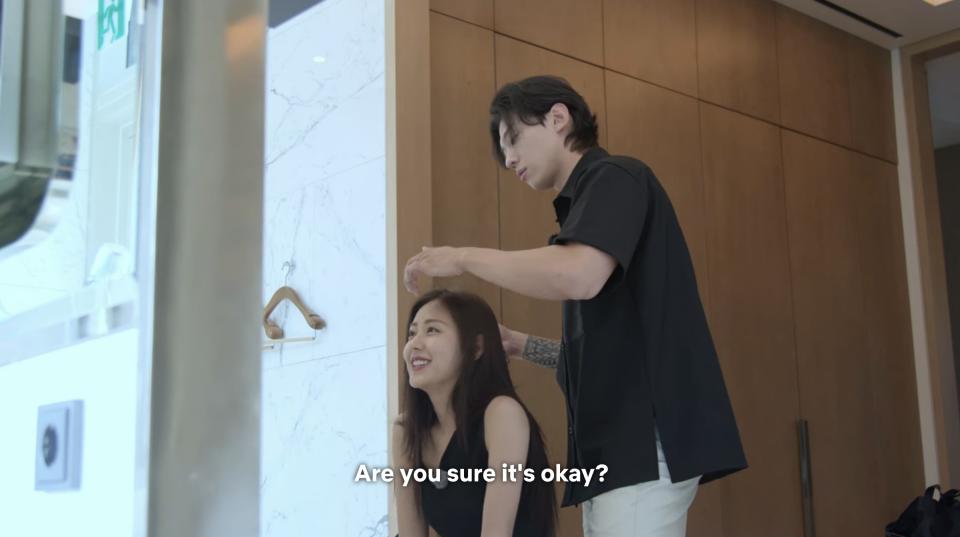 Seul-ki smiles and asks, "Are you sure it's okay?" while Jin-young straightens her hair