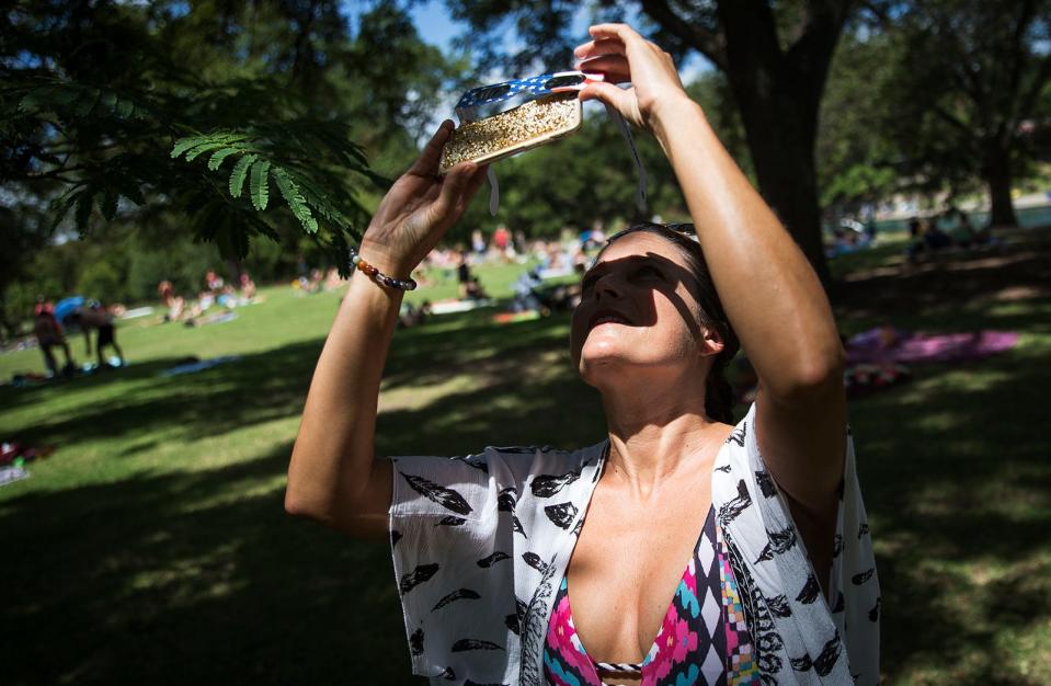 Carrie Hard holds protective glasses up to her phone to photograph the solar eclipse at Barton Springs Pool in August 2017.