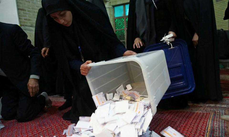 Poll workers empty ballot boxes after the election comes to an end in Tehran.