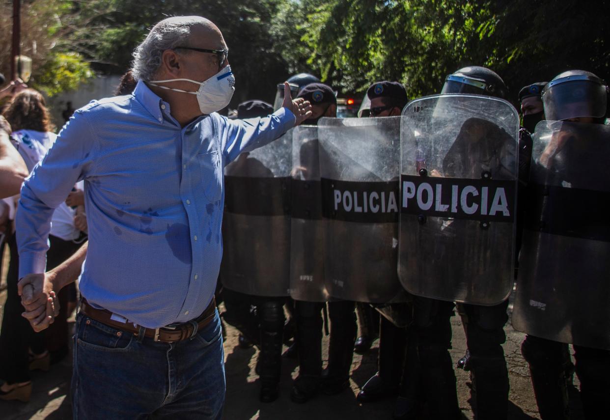 Nicaraguan journalist Carlos Fernando Chamorro, director of Confidencial and Esta Semana news media, is pushed away by riot police outside El Confidencial offices in Managua on December 14, 2020.