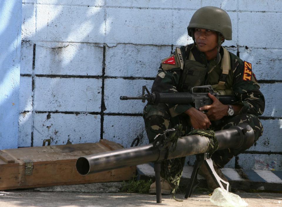 A government soldier squats next to a 90RR shoulder-fired rocket launcher while awaiting orders after Muslim rebels members of the Moro National Liberation Front (MNLF) occupied villages in Zamboanga city, southern Philippines September 9, 2013. Muslim rebels took 30 civilian hostages in the southern Philippines on Monday and held security forces in a standoff as part of a drive to derail peace talks, officials said. Police commandos cordoned off parts of Zamboanga City on the island of Mindanao after a rogue faction of the MNLF took hostages and tried to march to the city hall to raise their flag, an army commander said. REUTERS/STRINGER (PHILIPPINES - Tags: POLITICS MILITARY CIVIL UNREST)