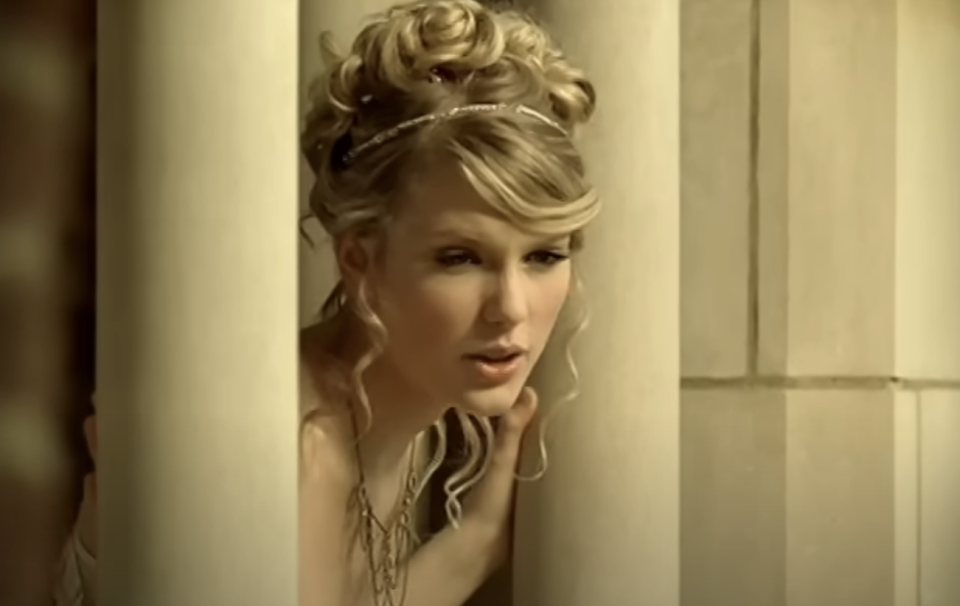 Taylor Swift in an elegant updo hairstyle peering around a corner