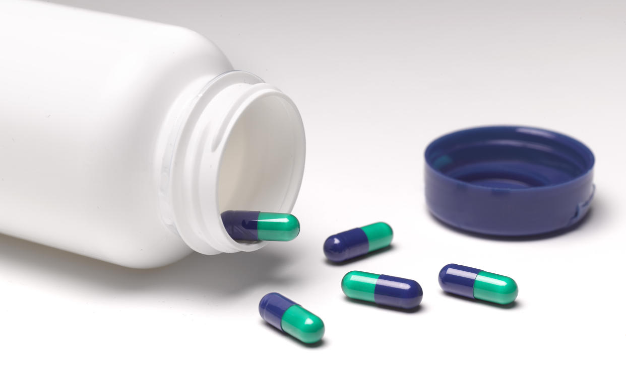 Capsules left lying on table, with open pill bottle