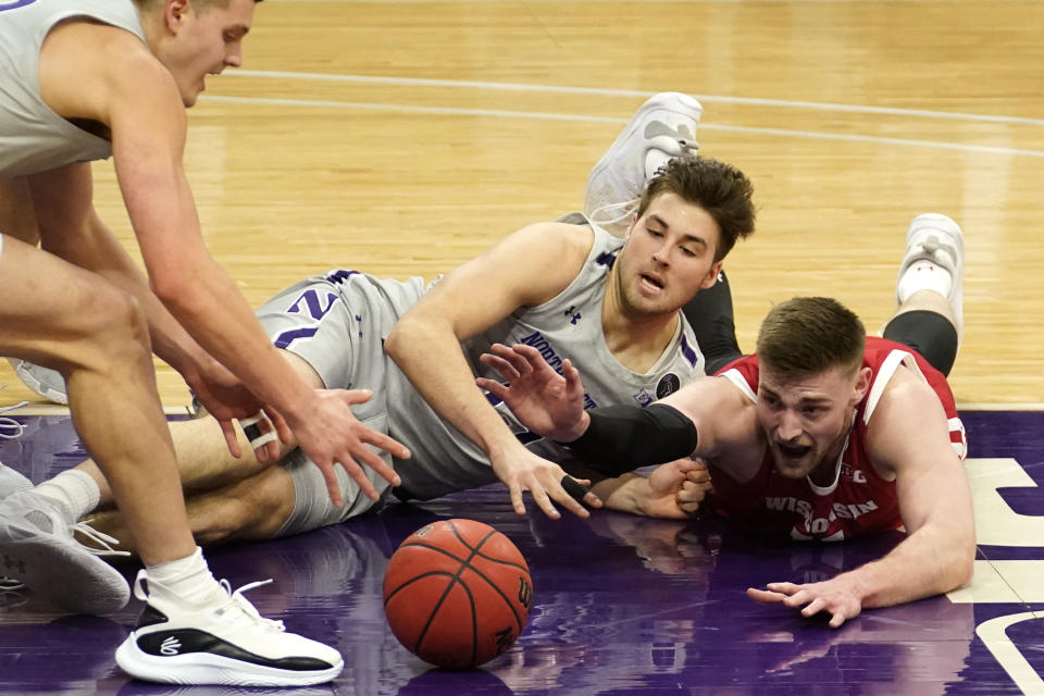 Wisconsin forward Micah Potter, right, battles for the ball against Northwestern forward Miller Kopp, left, and center Ryan Young during the first half of an NCAA college basketball game in Evanston, Ill., Saturday, Feb. 21, 2021. (AP Photo/Nam Y. Huh)