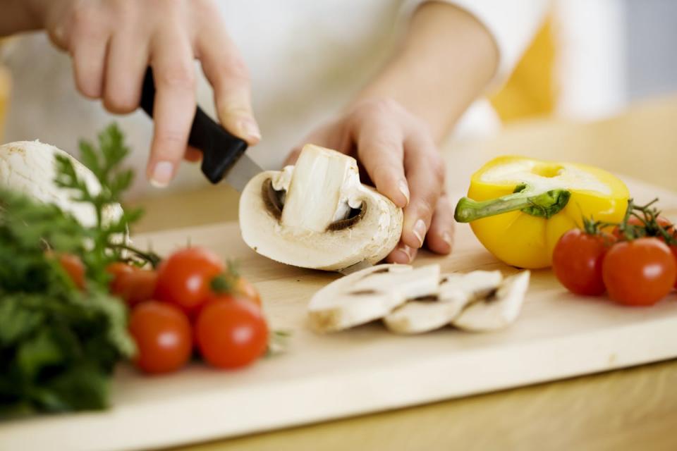 Hands seen chopping vegetables.