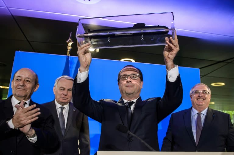 French President Francois Hollande (C) receives a model submarine from French naval defence contractor DCNS chief executive officer Herve Guillou (R) in Paris on April 26, 2016