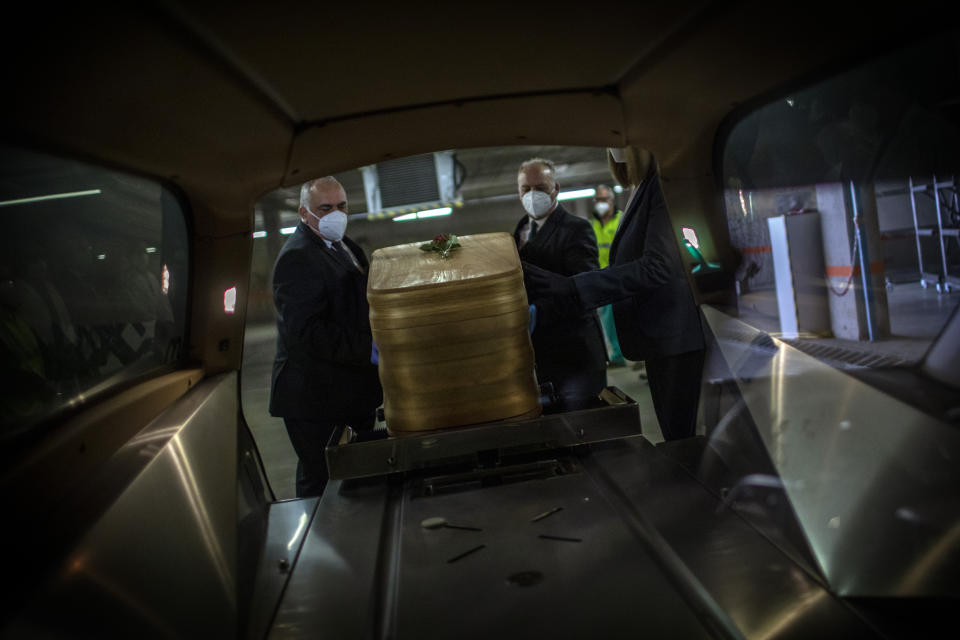 Mortuary service workers load inside a hearse the coffin of the last COVID-19 victim stored at an underground parking garage that was turned into a morgue, at the Collserola funeral home in Barcelona, Spain. May 17, 2020. A funeral home in Barcelona has closed a temporary morgue it had set up inside its parking garage to keep the victims of the Spanish city's coronavirus outbreak. The last coffin was removed and buried on Sunday. In 53 days of use, the temporary morgue has held more than 3,200 bodies. (AP Photo/Emilio Morenatti)