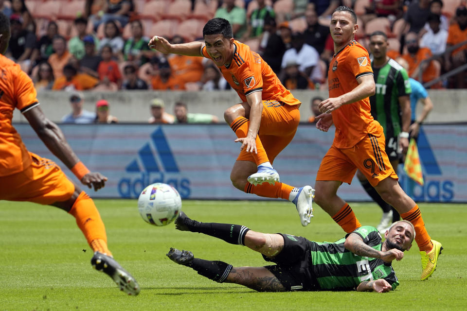 Houston Dynamo's Memo Rodríguez, center, leaps over Austin FC's Diego Fagúndez, bottom, during the first half of a MLS soccer match Saturday, April 30, 2022, in Houston. (AP Photo/David J. Phillip)