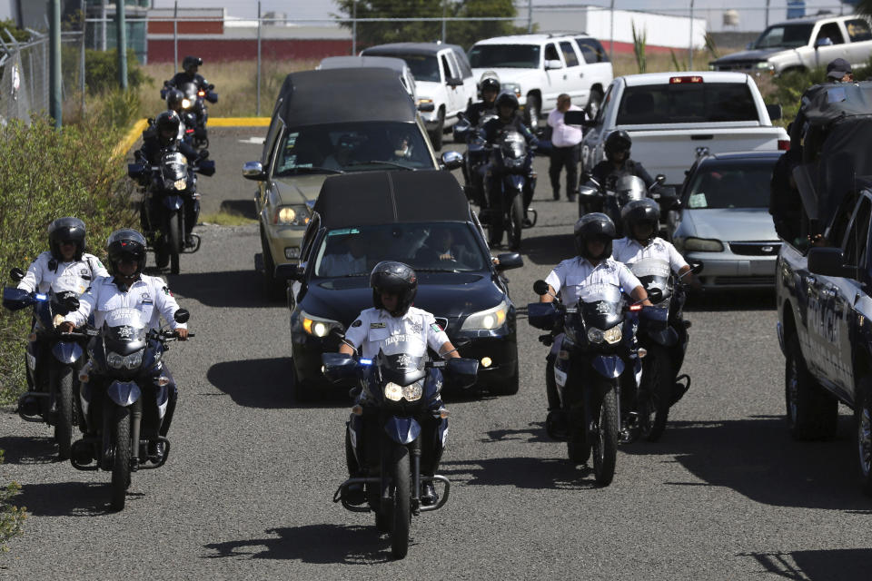 La policía escolta a una caravana de vehículos funerarios que transportan los cadáveres de policías mexicanos asesinados durante una aparente emboscada en Morelia, México, el martes 15 de octubre de 2019. (AP Foto/Marco Ugarte)