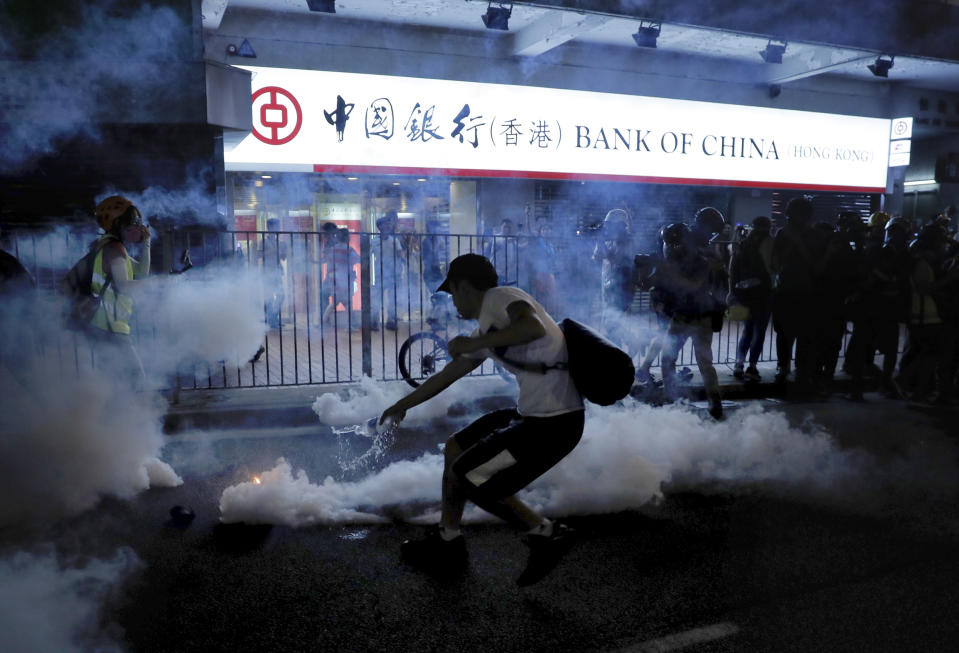 A protester tries to pour water on a tear gas canister as protesters battle with police on the streets of Hong Kong on Saturday, Sept. 21, 2019. Protesters in Hong Kong threw gasoline bombs and police fired tear gas Saturday in renewed clashes over anti-government grievances (AP Photo/Kin Cheung)