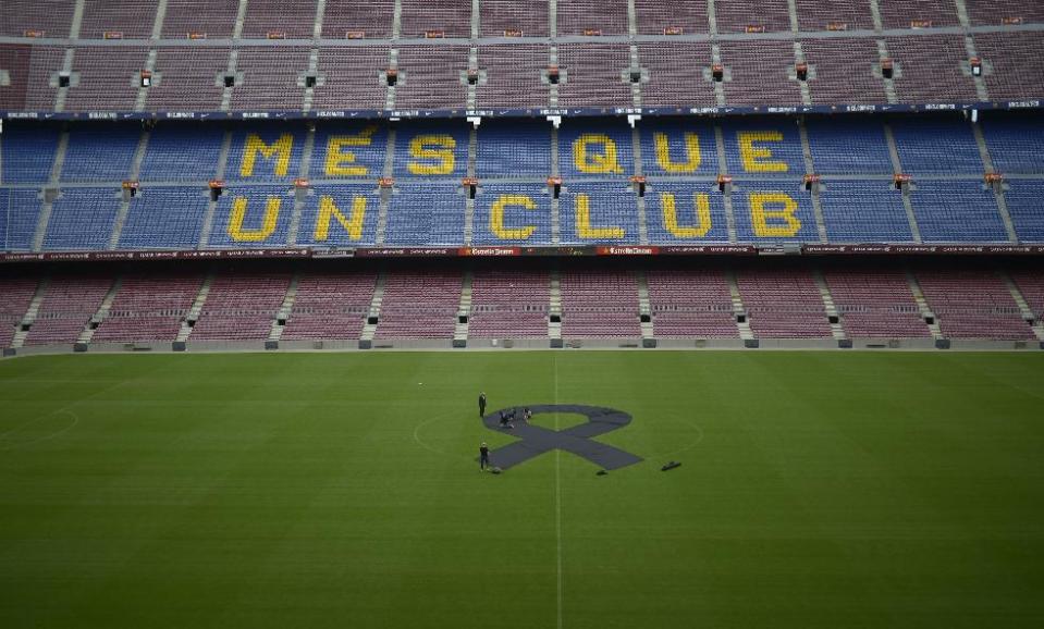 FC Barcelona's employees place a black sash mid-field in respect to late former FC Barcelona's coach Tito Vilanova at Camp Nou Stadium in Barcelona, Spain, Saturday, April 26, 2014. FC Barcelona announced on their web page Friday April 25, 2014, that Vilanova has died Friday following a long battle with throat cancer. He was 45. The sign on stands reads "More than a Club". (AP Photo/Manu Fernandez)