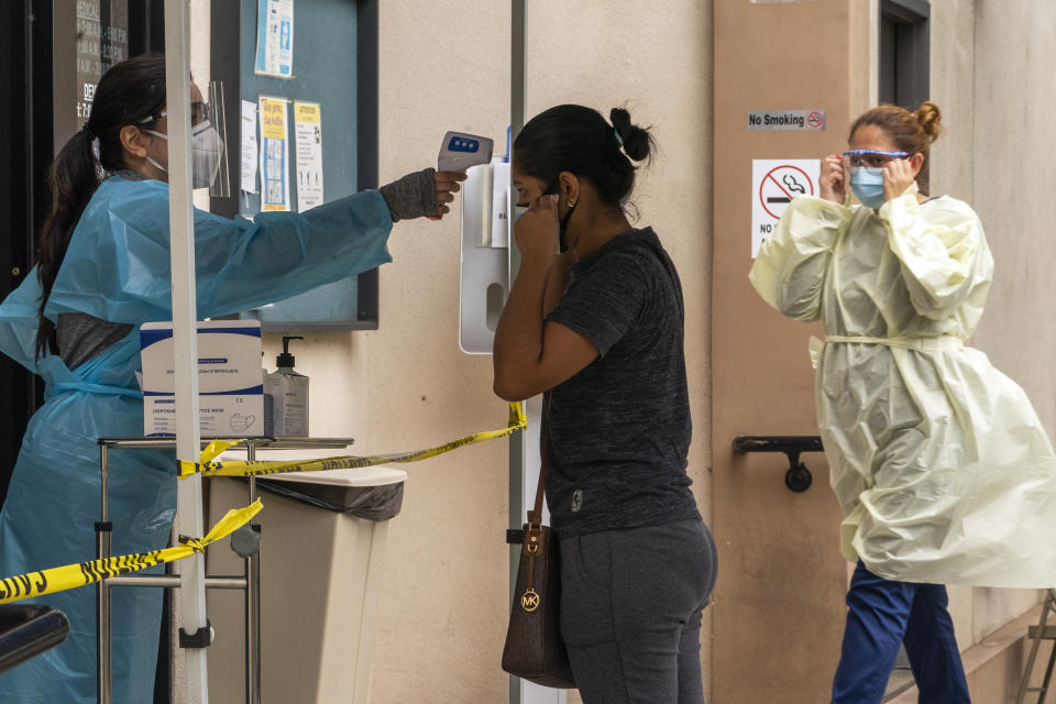 A patient has her body temperature screened after showing her COVID-19 vaccine card at the Clínica Monseñor Oscar A. Romero in the Pico-Union district of Los Angeles, Monday, July 26, 2021. The clinic is a COVID-19 vaccine site. California said it will require proof of vaccination or weekly testing for all state workers and millions of public- and private-sector health care employees starting in August. (AP Photo/Damian Dovarganes)