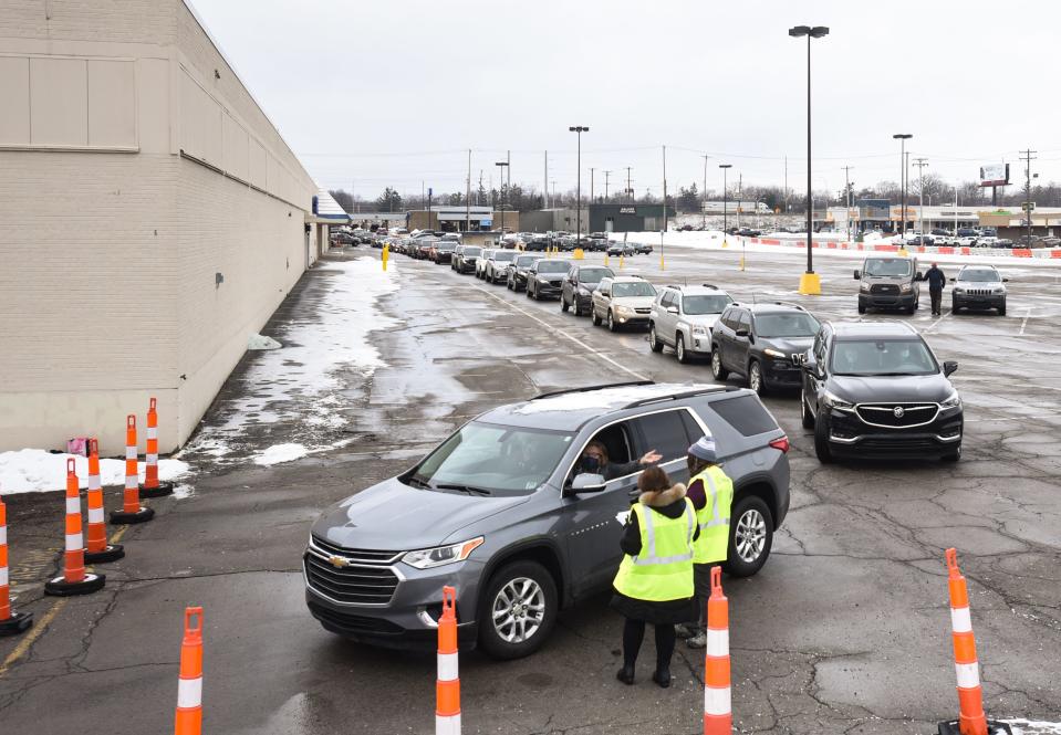 Workers from Sparrow Healthcare talk to a woman Tuesday, Jan. 19, 2021, as she approaches a checkpoint at the Sparrow Laboratories Drive-Thru Services site at Frandor Shopping Center in Lansing.