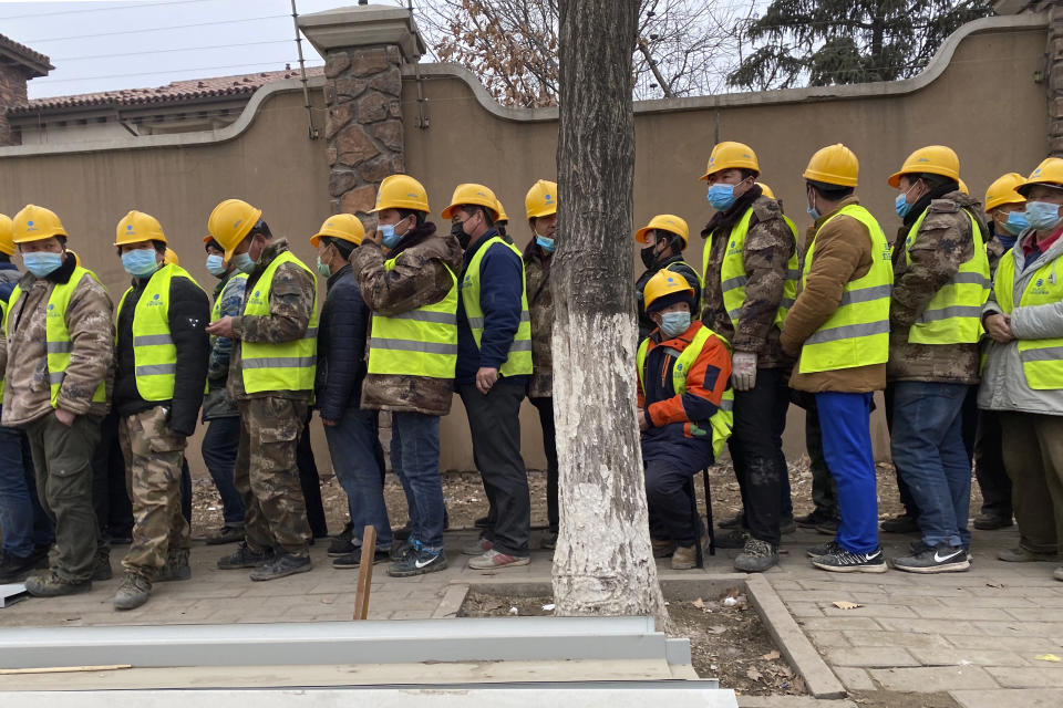 Workers line up for lunch outside a construction site of a hospital as part of plans to fight against a viral outbreak in Beijing, China on Thursday, Feb. 20, 2020. A viral outbreak that began in China has infected more than 75,000 people globally. The World Health Organization has named the illness COVID-19, referring to its origin late last year and the coronavirus that causes it. (AP Photo/Ng Han Guan)