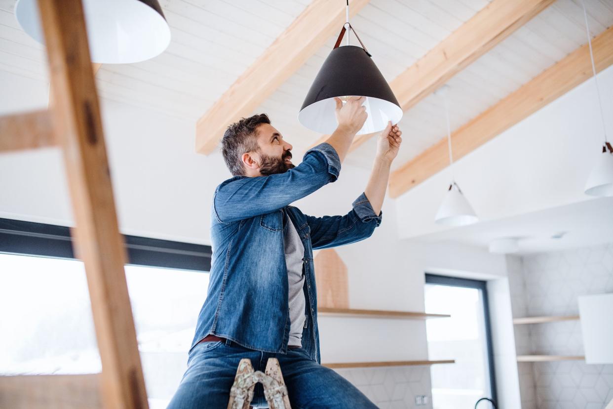 middle-aged man putting in new light fixture in room