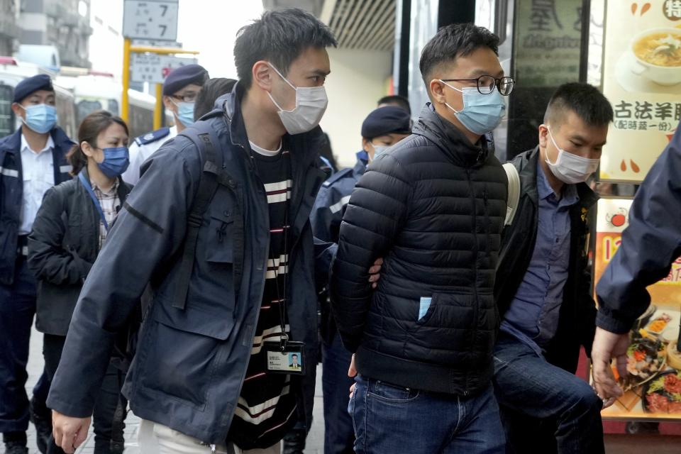 Editor of "Stand News" Patrick Lam, center, is arrested by police officers in Hong Kong, Wednesday, Dec. 29, 2021. Hong Kong police say they have arrested seveal current and former staff members of the online media company for conspiracy to publish a seditious publication. (AP Photo/Vincent Yu)