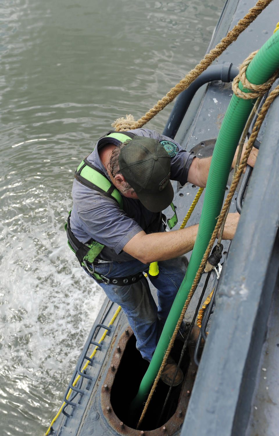 Norman Snipe climbs down into a tank on the port side of the USS Texas to reposition a pump hose Wednesday, June 13, 2012, in Houston. The 100-year-old battleship's hull sprung a leak five days ago and has been taking on as much as 1,000 gallons of seawater every minute as workers struggle to contain it. (AP Photo/Pat Sullivan)