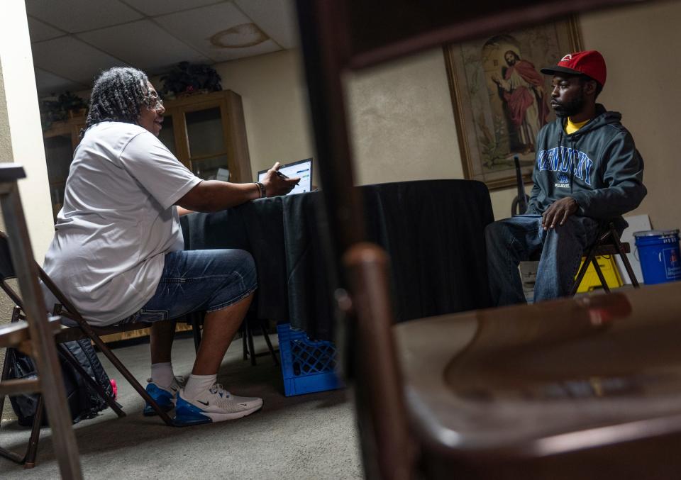 Community & Home Supports resource navigator Timothy Desaussure Jr., left, helps get Ronald Harris, 39, signed up for assistance at  St. John's Community Center in Detroit on Wednesday, May 31, 2023.