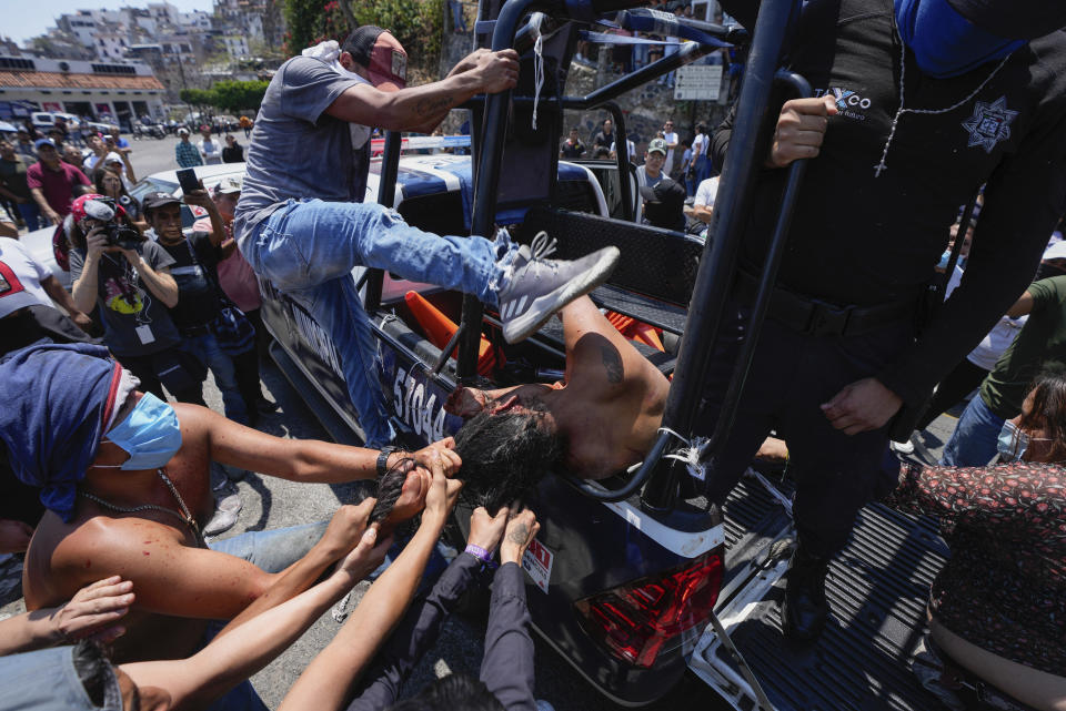 A woman suspected in the kidnapping and killing of an 8-year-old girl, is dragged out of a police vehicle by a mob in Taxco, Mexico, Thursday, March 28, 2024. Police then picked her up off the ground and took her away. The Guerrero state prosecutors’ office later confirmed the woman died of her injuries. (AP Photo/Fernando Llano)