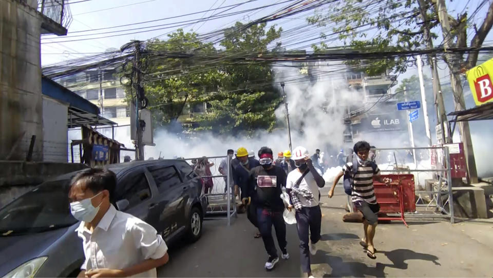 In this image from a video, anti-coup protesters run away from tear gas launched by security forces in Yangon, Myanmar Monday, March 1, 2021. Defiant crowds returned to the streets of Myanmar's biggest city on Monday, determined to continue their protests against the military's seizure of power a month ago, despite security forces having killed at least 18 people around the country just a day earlier. (AP Photo)