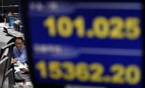 An employee of a foreign exchange trading company works near a monitor displaying the Japanese yen's exchange rate against the U.S. dollar (top), and Nikkei share average in Tokyo November 22, 2013. Japanese stocks scaled six-month peaks on Friday as the yen took a spill, though other Asian markets lagged as investors resigned themselves to an inevitable slowdown in U.S. stimulus. REUTERS/Toru Hanai