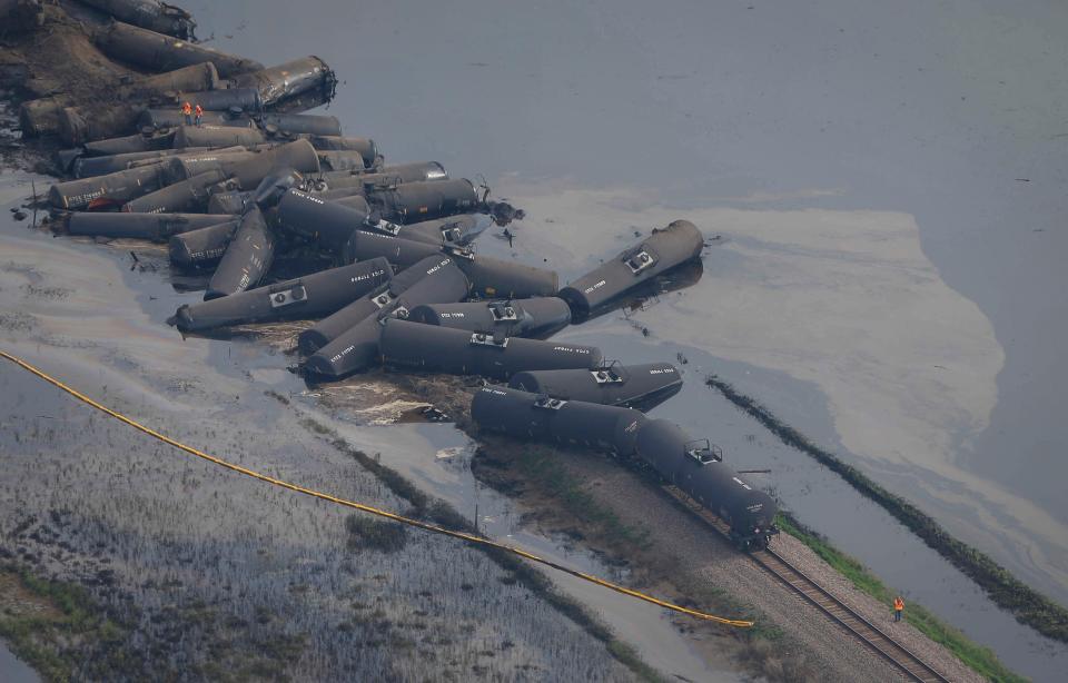 Crews work to clean up cars from the BNSF railway after a 31-car derailment dumped crude oil into the Little Rock River on Friday, June 22, 2018, in Doon.