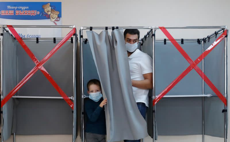 Man with a boy exit a voting booth at a polling station in Tomsk