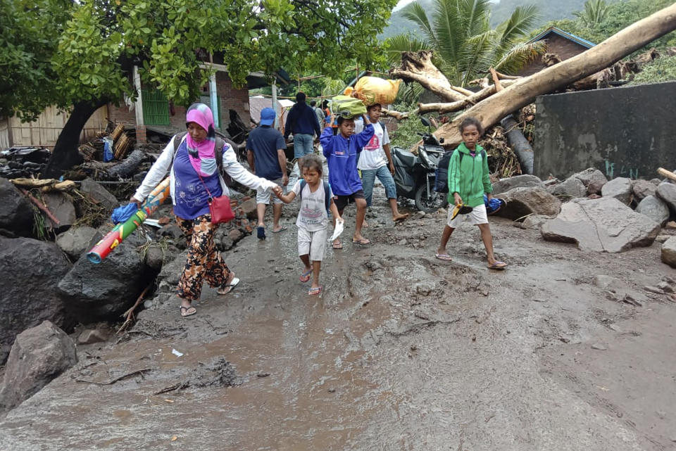 People walk amid debris at a village affected by flood in Ile Ape, on Lembata Island, East Nusa Tenggara province, Indonesia, Sunday, April 4, 2021 photo. Multiple disasters caused by torrential rains in eastern Indonesia have left dozens of people dead or missing while displacing thousands, the country's disaster relief agency said Monday. (AP Photo/Ricko Wawo)