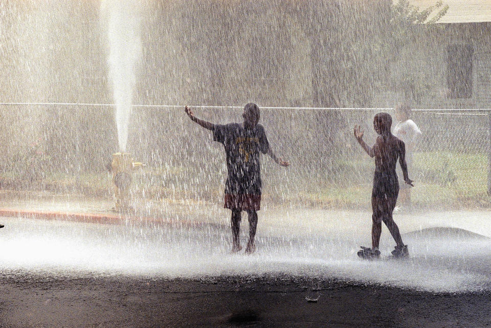 Children in the South Central section of Los Angeles play in water from a fire hydrant during a heat wave in August 1997 