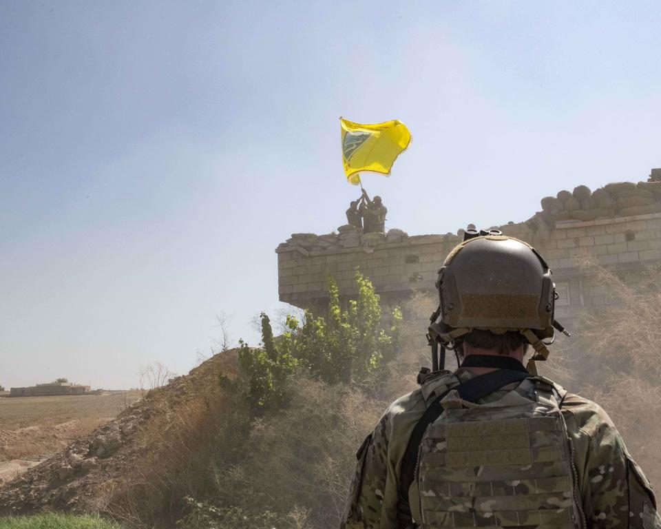 In this Sept. 21, 2019, photo, released by the U.S. Army, a U.S. soldier oversees members of the Syrian Democratic Forces as they demolish a Kurdish fighters' fortification and raise a Tal Abyad Military Council flag over the outpost as part of the so-called "safe zone" near the Turkish border. (U.S. Army photo by Staff Sgt. Andrew Goedl via AP)