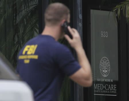 A Federal and state law enforcement official walks outside the office of Med-Care Diabetic and Medical Supplies company during a raid in Boca Raton, Florida, January 14, 2015. REUTERS/Andrew Innerarity