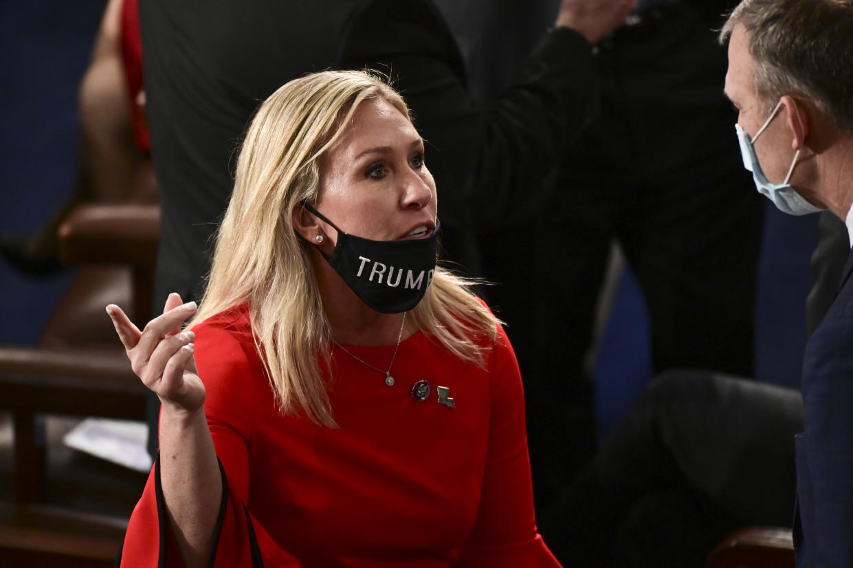 Rep. Marjorie Taylor Greene (R-GA) with her "Trump Won" face mask pulled down speaking to a colleague. (Photo by Erin Scott-Pool/Getty Images)