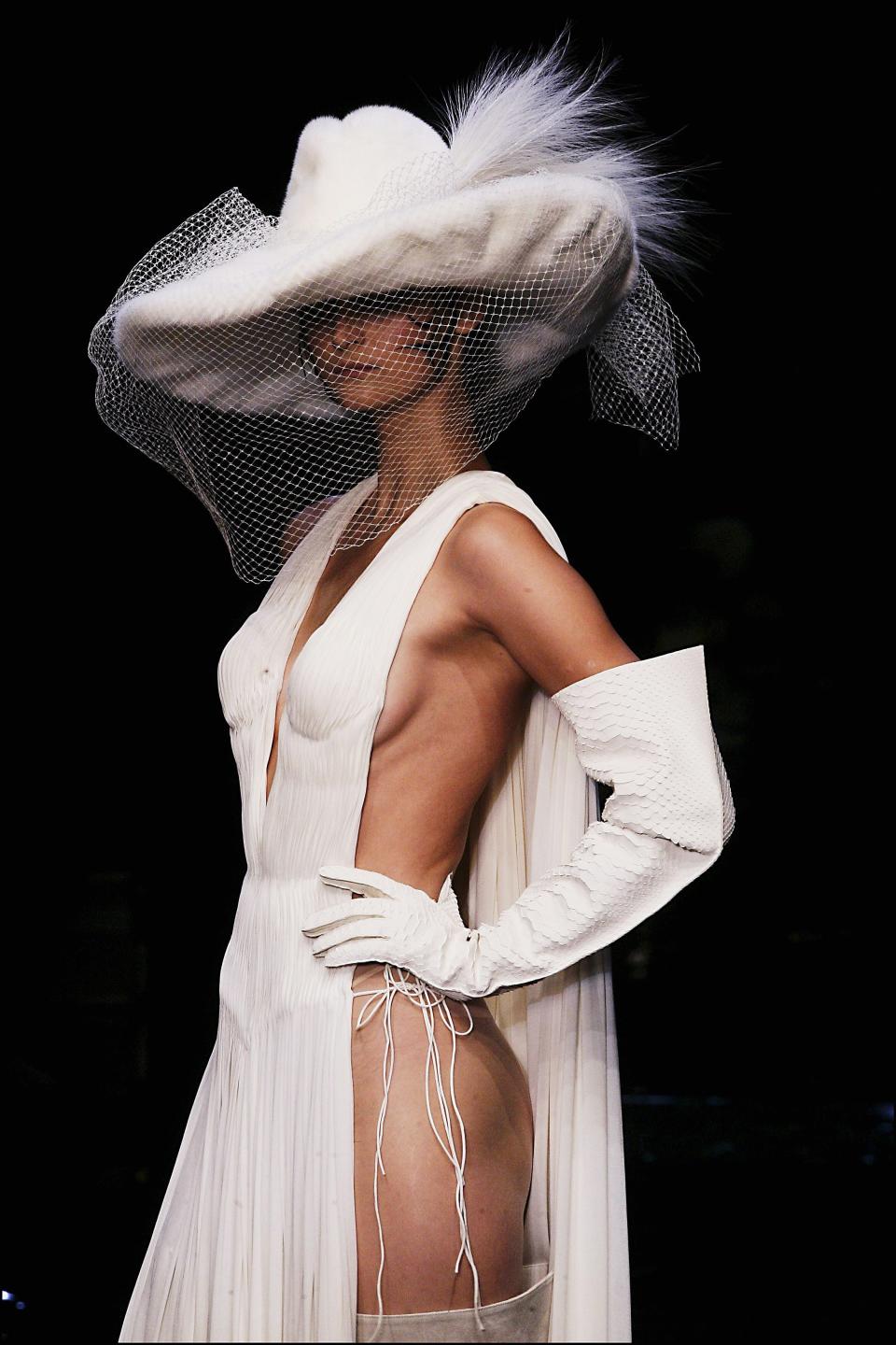 Eine klassische Braut gibt es JPG nicht. Bei seiner Couture-Show 2004 ließ er seine Braut zwar in weiß, aber mit Sideboob statt hochgeschlossener Spitze über den Laufsteg stolzieren. Accessoires wie ein übergroßer Cowboy-Hut, oberschenkelhohen Stiefeln und langen Handschuhe machten den Look komplett. (Bild: Getty Images)