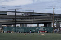 A person kicks a soccer ball as a truck drives above Raimondi Park in Oakland, Calif., Thursday, Feb. 18, 2021. Disadvantaged communities in America are disproportionately affected by pollution from industry or waste disposal, but their complaints have few outlets and often reach a dead end. (AP Photo/Jeff Chiu)