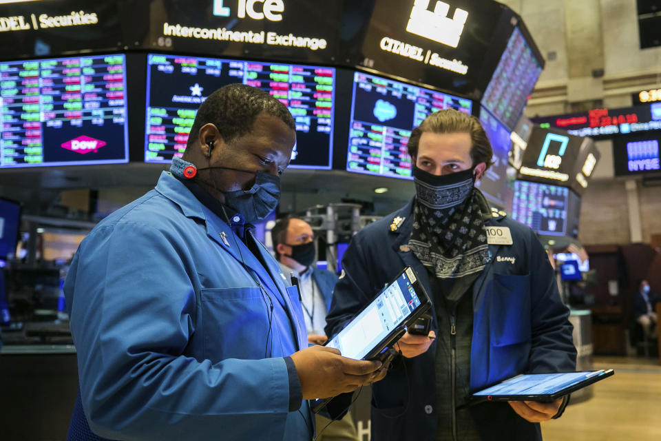 In this photo provided by the New York Stock Exchange, traders Thomas Lee, left, and Benjamin Tuchman work on the floor Friday, Nov. 20, 2020. U.S. stocks are pulling a bit lower in midday trading Friday as worries about the worsening pandemic weigh on rising optimism about a coming coronavirus vaccine. (Courtney Crow/New York Stock Exchange via AP)