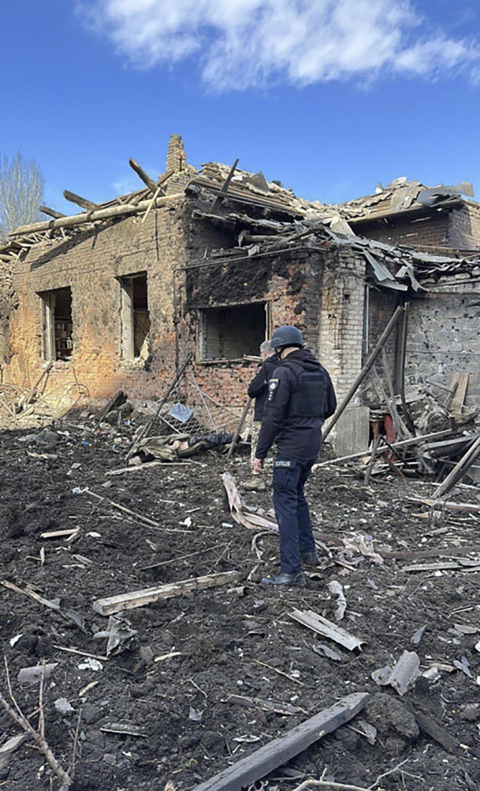 In this photo provided by the Ukrainian Interior Ministry Press Office, a police officer inspects the site of the Russian deadly missile attack in Kostiantynivka, Donetsk region, Ukraine, Sunday, April 2, 2023. (Ukrainian Interior Ministry Press Office via AP)