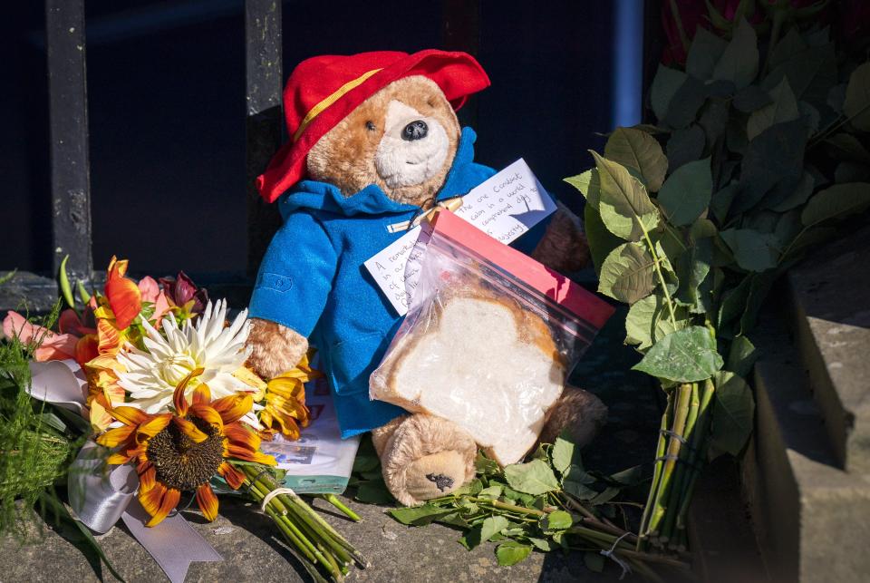 A Paddington Bear toy and marmalade sandwich is left amongst flowers (Jane Barlow/PA) (PA Wire)