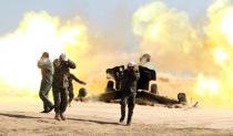 Volunteer Shiite fighters, who are supporting the Iraqi government forces in the fight against the Islamic State (IS) group fire a Howitzer artillery canon in the village of Awaynat near the city of Tikrit on February 28, 2015