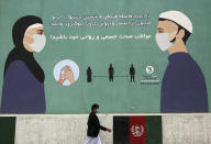 FILE-In this May 11, 2020, photo, a man wearing a protective face mask to help curb the spread of the coronavirus, walks past a painted wall of Ministry of Public Health, which gives instructions on measures to help curb the spread of the coronavirus in Kabul, Afghanistan. A prominent international aid organization warned Tuesday, June 2, 2020 that Afghanistan is on the brink of a humanitarian disaster because the government is unable to test at least 80% of possible coronavirus cases. (AP Photo/Rahmat Gul, File)