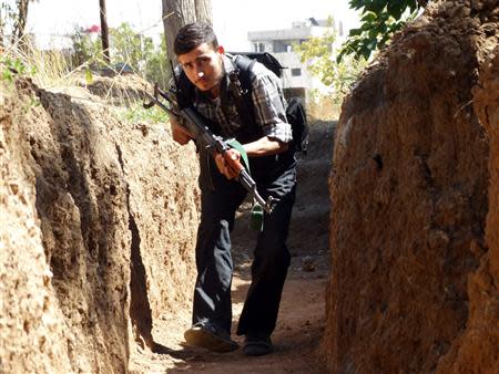 A Free Syrian Army fighter moves along a trench with his weapon to avoid forces loyal to Syria's President Bashar al-Assad in eastern al-Ghouta, near Damascus September 8, 2013. Picture taken September 8, 2013. REUTERS/Msallam Abd Albaset