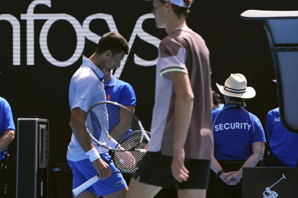 Novak Djokovic, left, of Serbia walks past Jannik Sinner of Italy during their semifinal at the Australian Open tennis championships at Melbourne Park, Melbourne, Australia, Friday, Jan. 26, 2024. (AP Photo/Andy Wong)