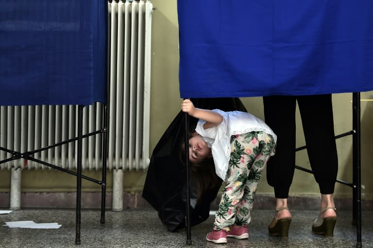A girl looks out of a voting booth during the Greek referendum in Athens