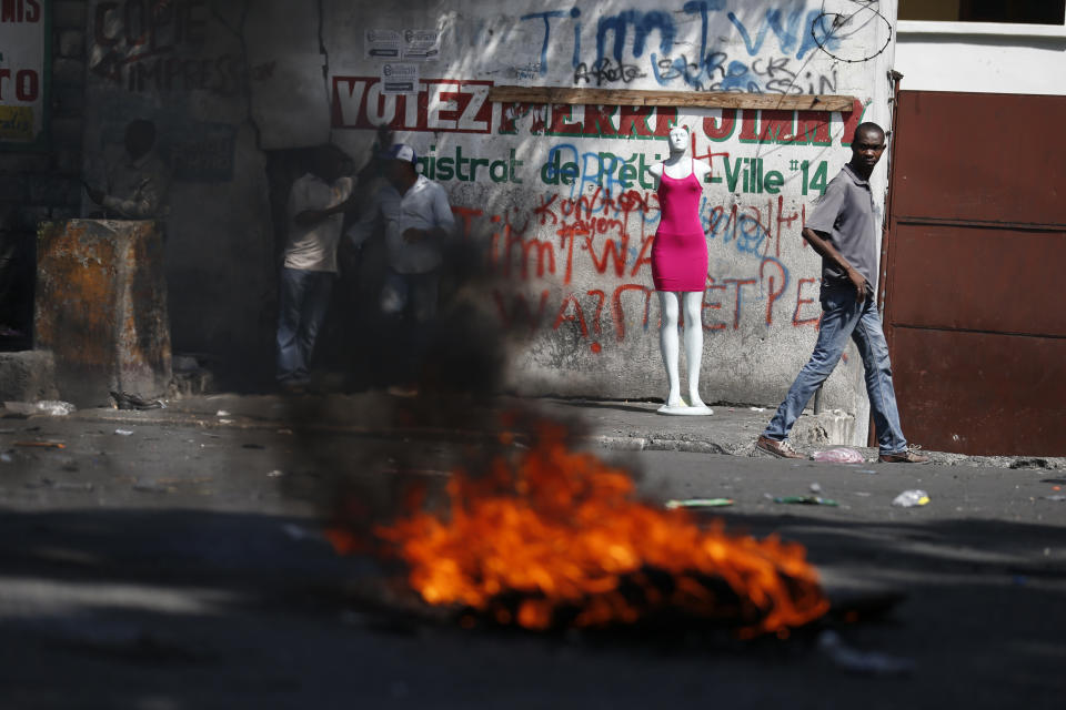 A man walks past a burning barricade during anti-government protests in Port-au-Prince, Haiti, Friday, Oct. 11, 2019. Protesters burned tires and spilled oil on streets in parts of Haiti's capital as they renewed their call for the resignation of President Jovenel Moïse just hours after a journalist was shot to death. (AP Photo/Rebecca Blackwell)