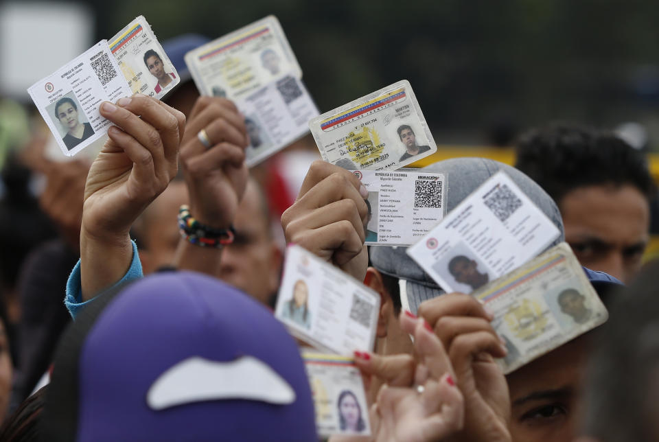 <p>Venezuelan citizens hold up their identification cards for inspection by the Colombian immigration police, in Cucuta, Colombia, on the border with Venezuela on Feb. 22, 2018. (Photo: Fernando Vergara/AP) </p>