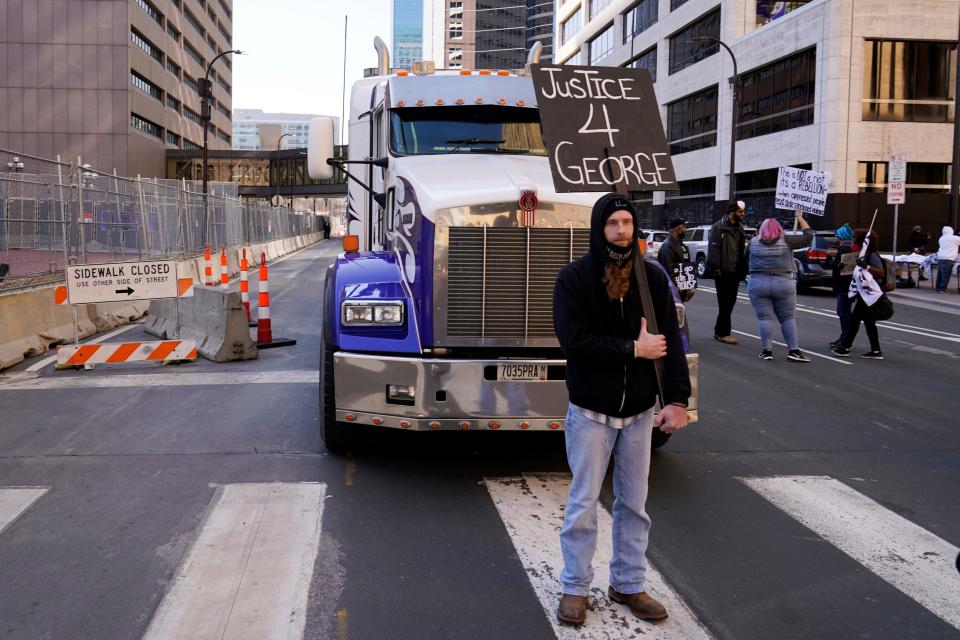 A unidentified protester blocks a truck on a street next to the Hennepin County Government Center as protesters held vehicles at bay until they honked their horns Monday, March 29, 2021, in Minneapolis. The trial for former Minneapolis police officer Derek Chauvin began with opening statements from both sides. Chauvin is charged with murder in the death of George Floyd during an arrest last May in Minneapolis. (AP Photo/Jim Mone) ORG XMIT: M109