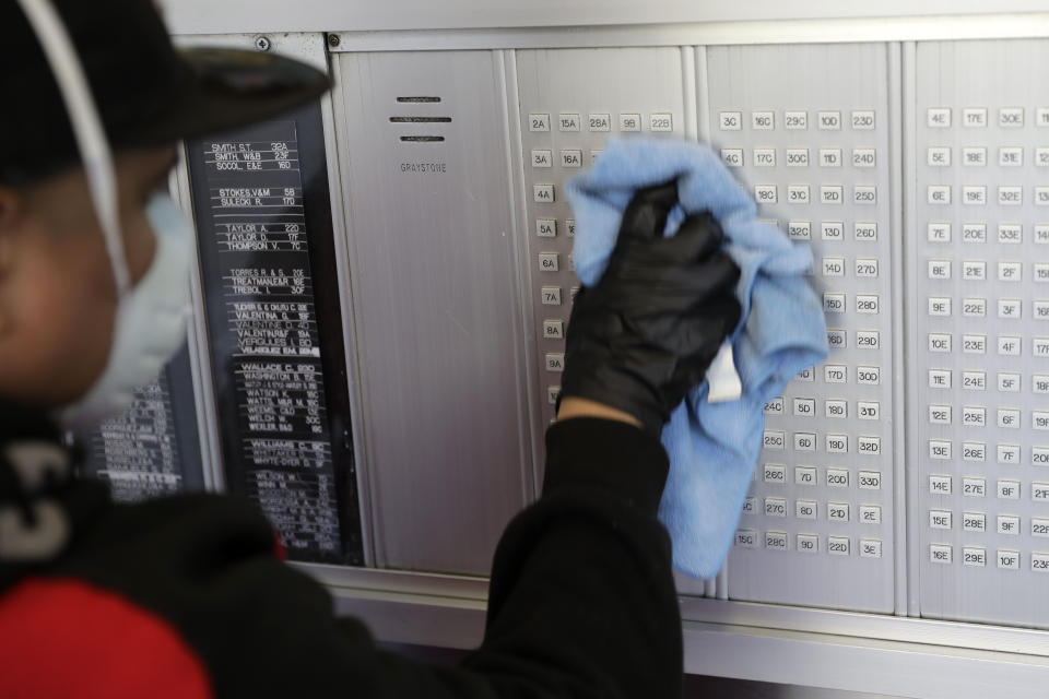 Guadalupe Lucero, a member of the janitorial staff, wipes down high-touch surfaces at a building in Co-op City in the Bronx, New York, Wednesday, May 13, 2020. Regular cleanings occur throughout the common areas of the buildings while the heavy disinfecting occurs in response to specific incidents, in this case reports of two coronavirus cases on the same floor. Within the Bronx, almost no place has been hit as hard as Co-op City. Data released by city health officials Monday revealed that the virus has killed at least 155 people living in the zip code that covers the complex. That’s roughly 1 of every 282 residents. (AP Photo/Seth Wenig)