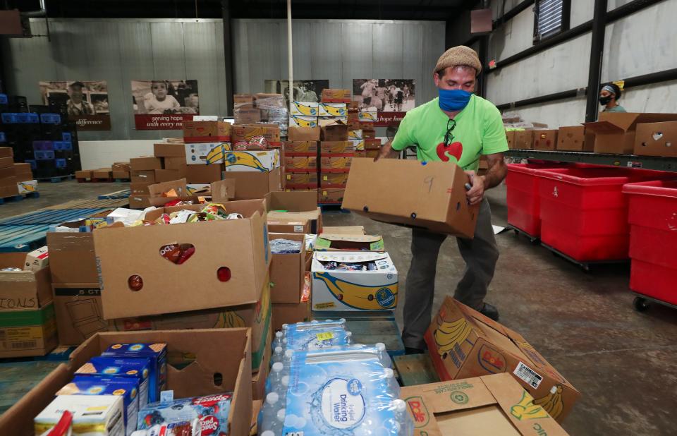 Dare to Care employee Eddie Vega grabs a box of donated items at the facility on Fern Valley Road in Louisville, Ky. on Nov. 17, 2020.  The items were donated by local grocery stores and will be sorted by volunteers and then distributed to regional charities. 