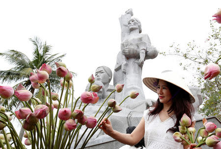 A woman arranges flowers in front of a monument in a museum, during the 50th anniversary of the My Lai massacre in My Lai village, Vietnam March 15, 2018. REUTERS/Kham